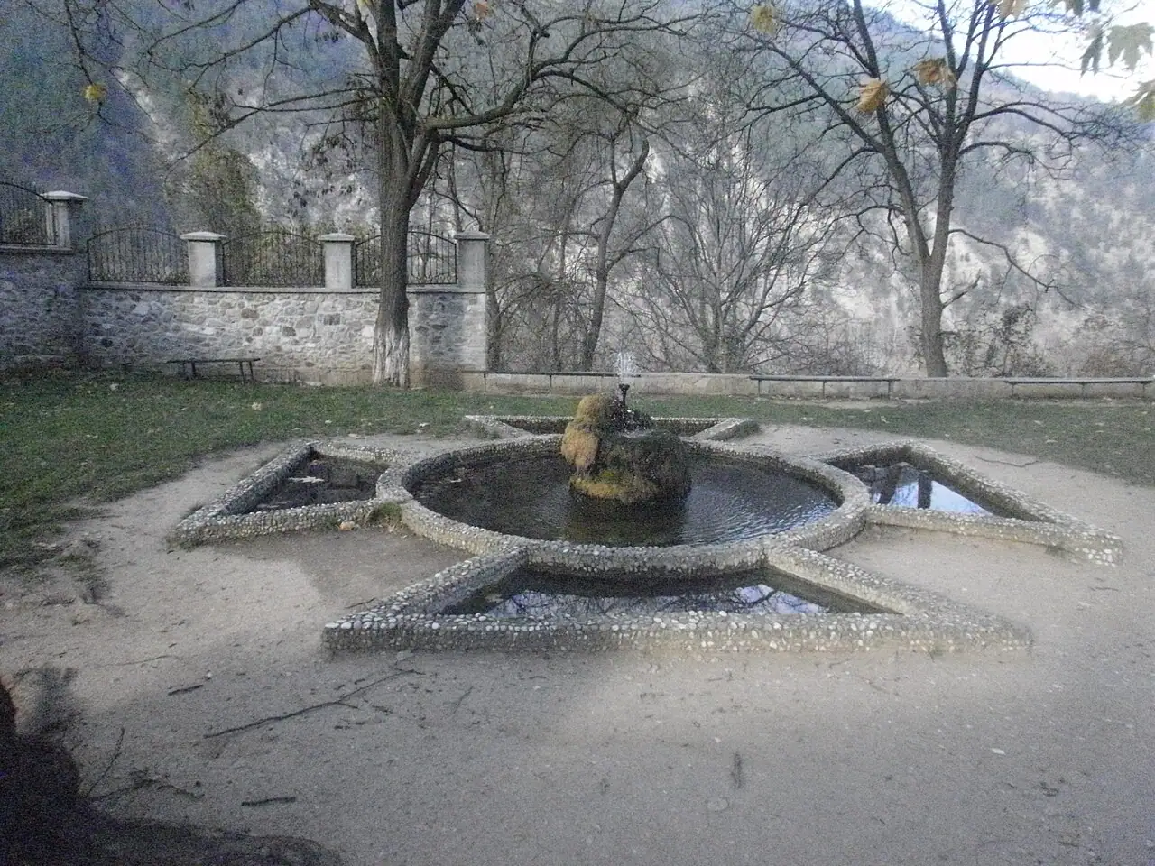 A star-shaped stone fountain in the terrace of Bachkovo Monastery with the wooded Rhodope slopes behind