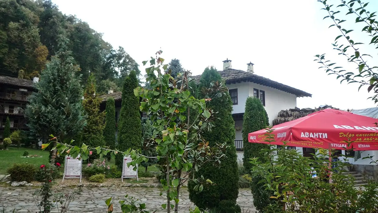 Troyan Monastery courtyard with wooden galleries, church dome and tall trees