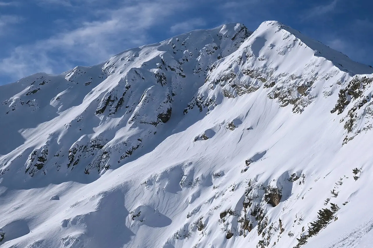 Several skiers in colourful jackets lined up on a gentle Bansko slope during a group lesson