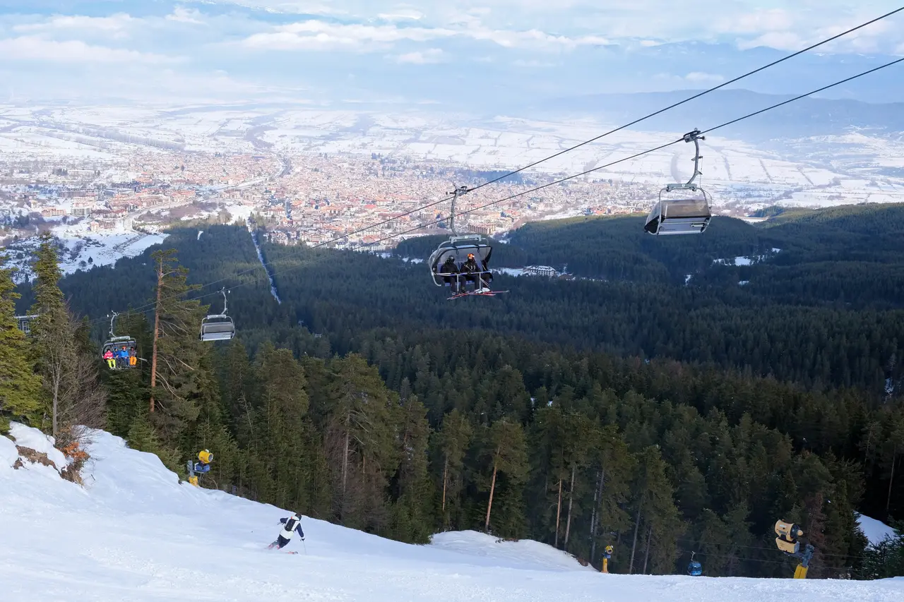 A Bansko chairlift high above the pine forest with the town of Bansko spread across the valley floor far below