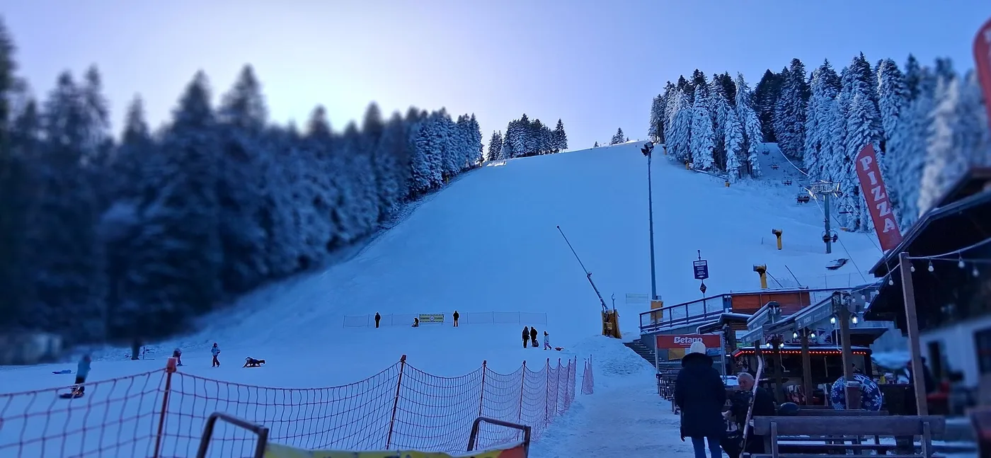 Panorama of the Borovets ski resort in winter, snow-covered pistes running down through pine forest to the cluster of hotels at the base