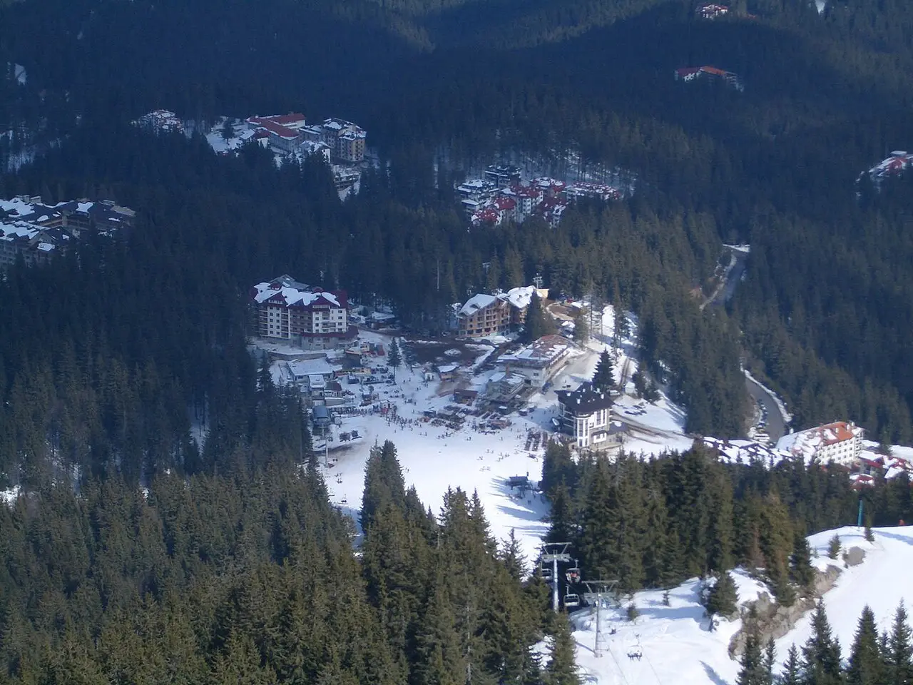 Aerial view of the Pamporovo resort base and ski clearing ringed by dense Rhodope spruce forest