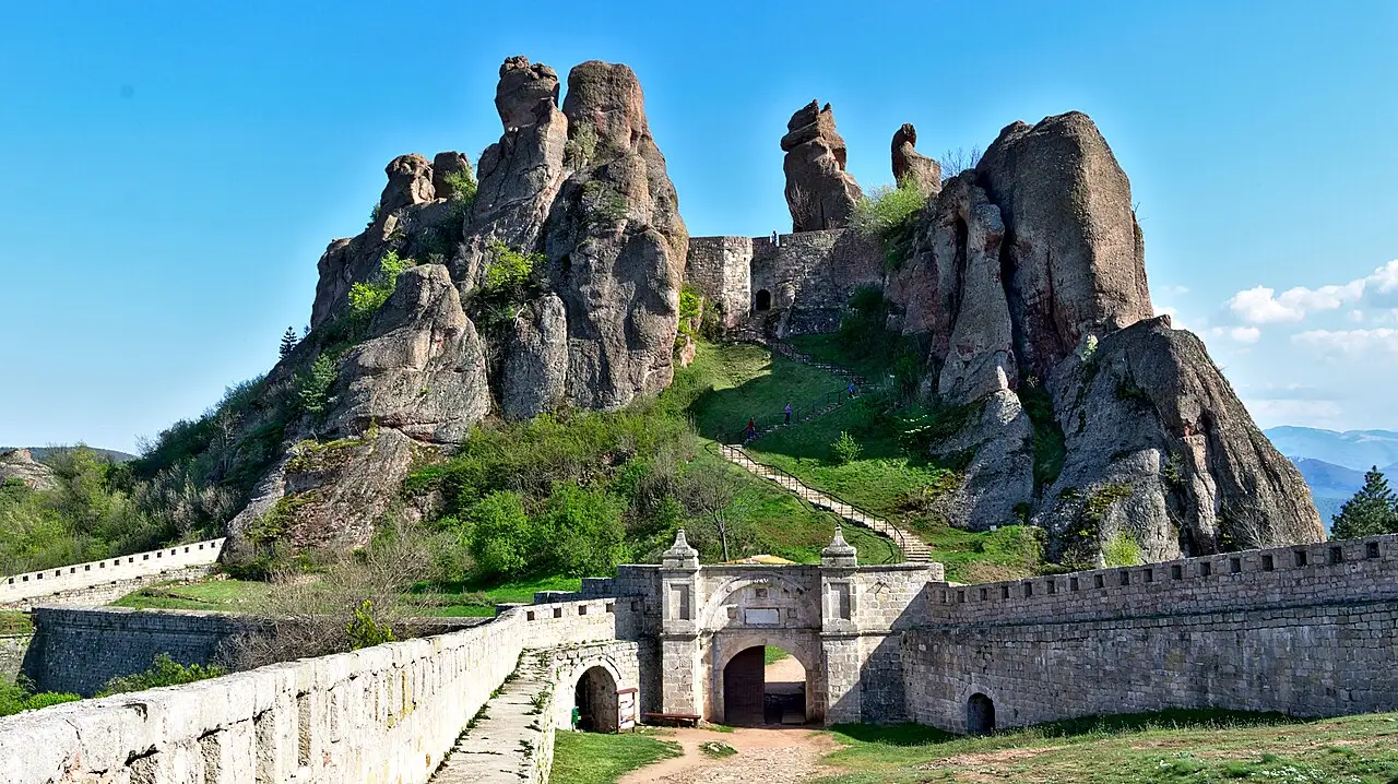 The stone gate and bridge of Belogradchik fortress with the towering red rock pinnacles rising behind it