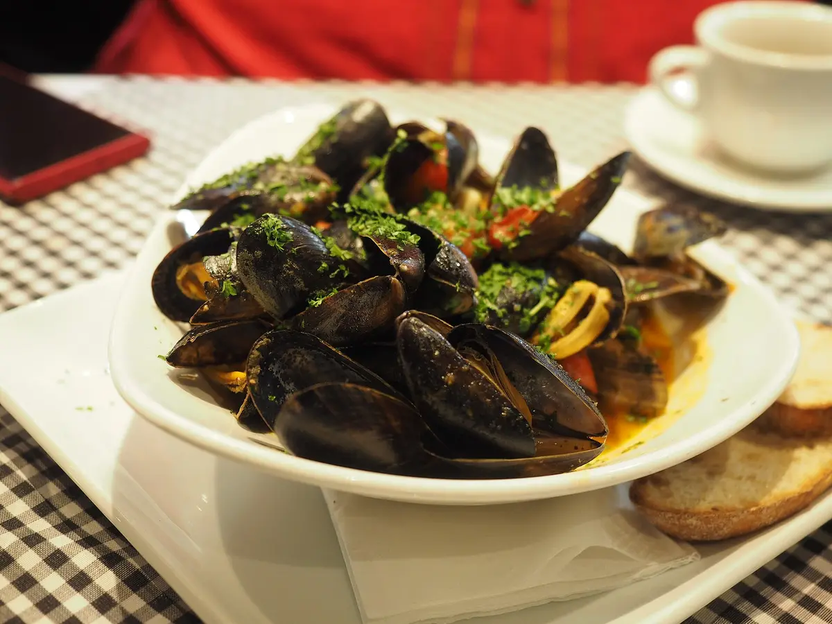 A large bowl of cooked mussels in shells on a restaurant table