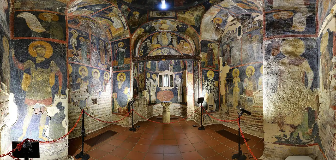 Wide view of the frescoed interior of Boyana Church, walls covered floor to ceiling with medieval saints and scenes