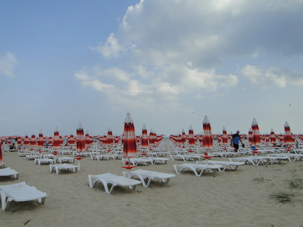 Hundreds of white sunbeds in rows under red and white parasols on the wide sandy beach at Albena