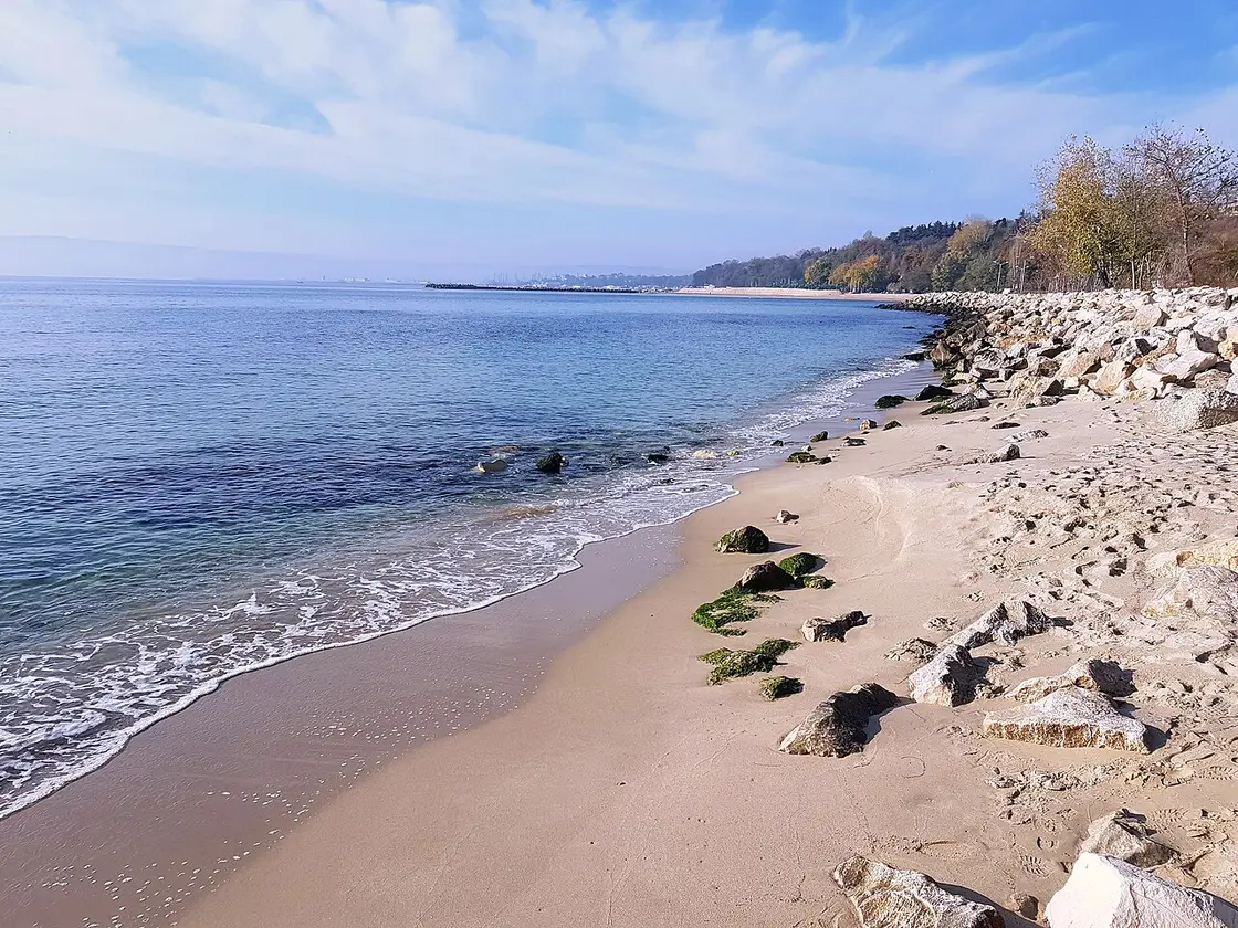 A calm Black Sea beach at Varna with clear water, sand and rocks, the coastline stretching into the distance