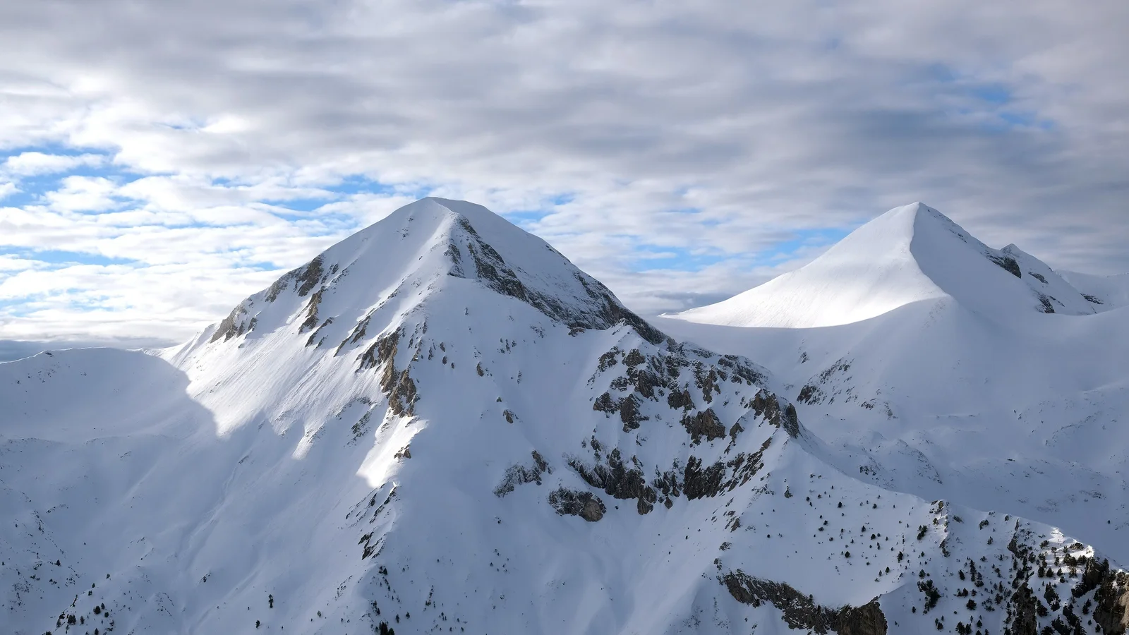 The snow-covered summits of Vihren and Kutelo in the Pirin mountains under a broken winter sky