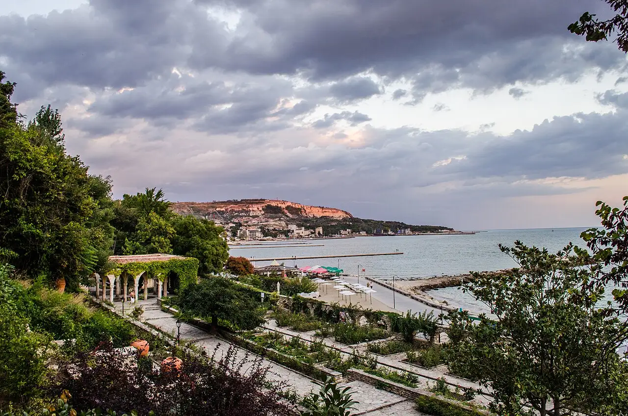 The terraced Botanical Garden at Balchik descending a cliff to the sea, stone-walled beds and a vine-covered pavilion above the bay