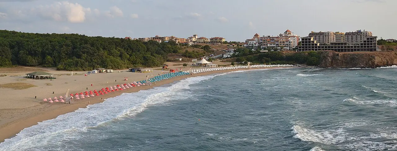 The wide curve of Butamiata beach at Sinemorets, sandy bay dotted with umbrellas below a forested headland deep in the Strandzha Nature Park