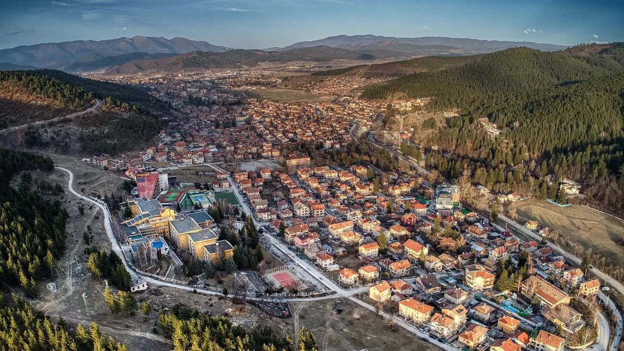 Aerial view of Velingrad stretched along a green Rhodope valley with forested ridges beyond the town