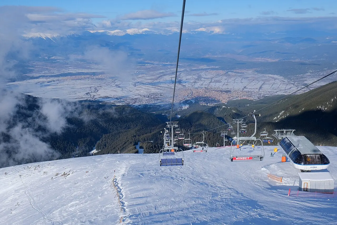 A groomed ski run winding down through pine forest at the Bansko resort in the Pirin mountains