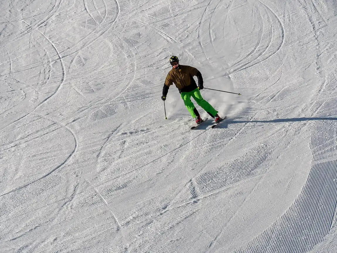 A skier carving a turn down a groomed piste at Sölden with fresh tracks visible in the snow