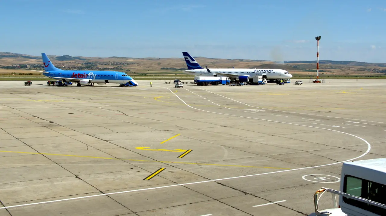 Charter aircraft parked on the apron at Burgas Airport under a clear sky with low hills behind