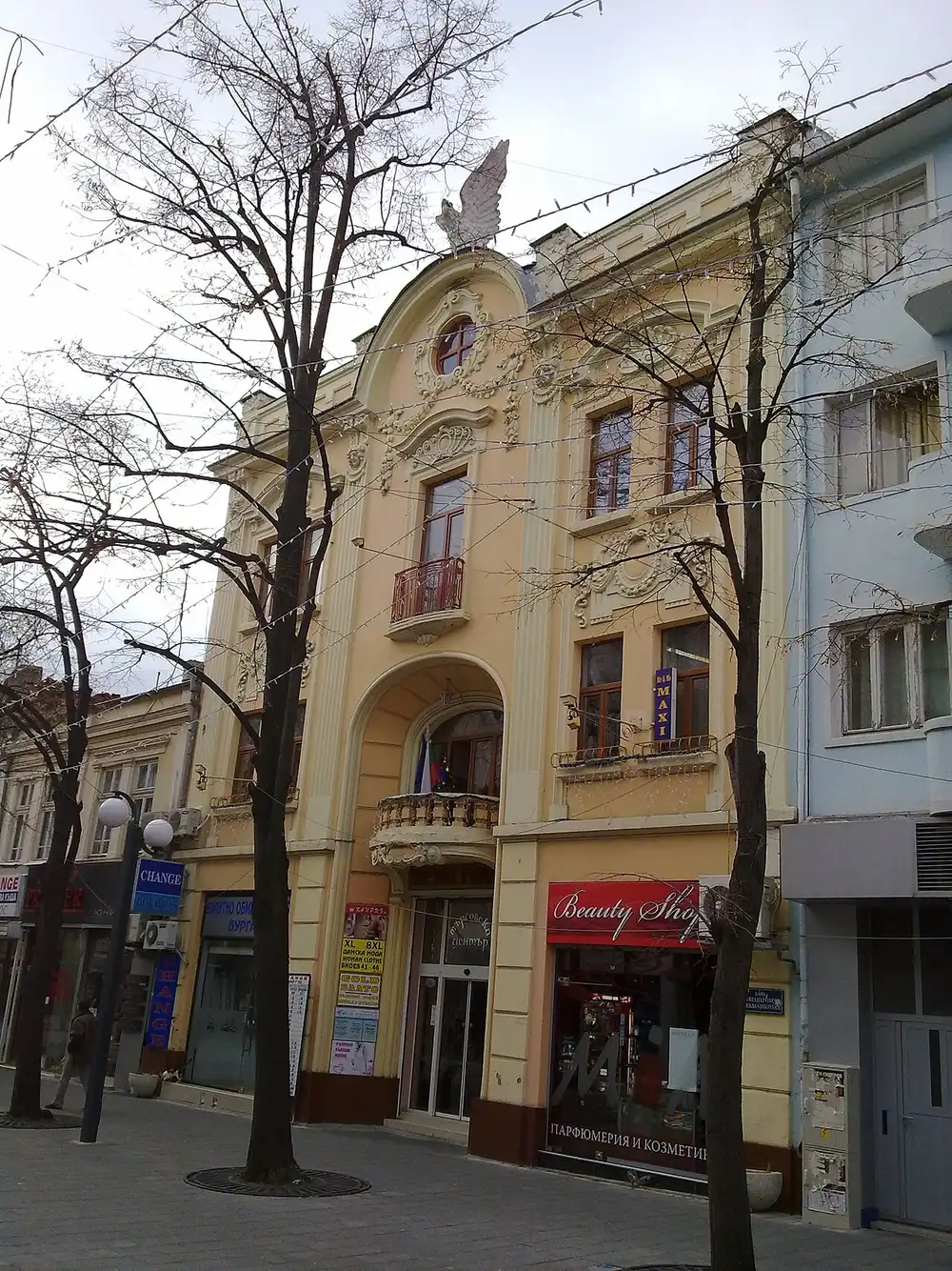 An ornate cream-coloured Secession-era building topped by a stone eagle on the pedestrian Aleksandrovska street in central Burgas