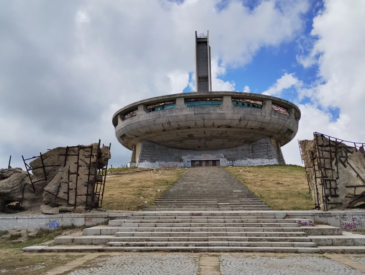 The long flight of concrete steps leading up to the Buzludzha monument, flanked by timber barriers, with the saucer above