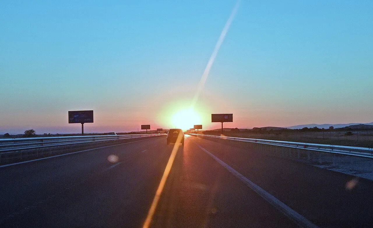 The A1 Trakia motorway in Bulgaria running straight through green farmland toward distant hills under a blue sky