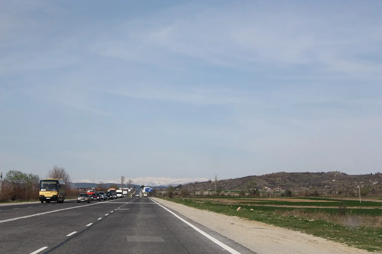 A two-lane road curving through forested green mountains on the way between Rila Monastery and Sofia