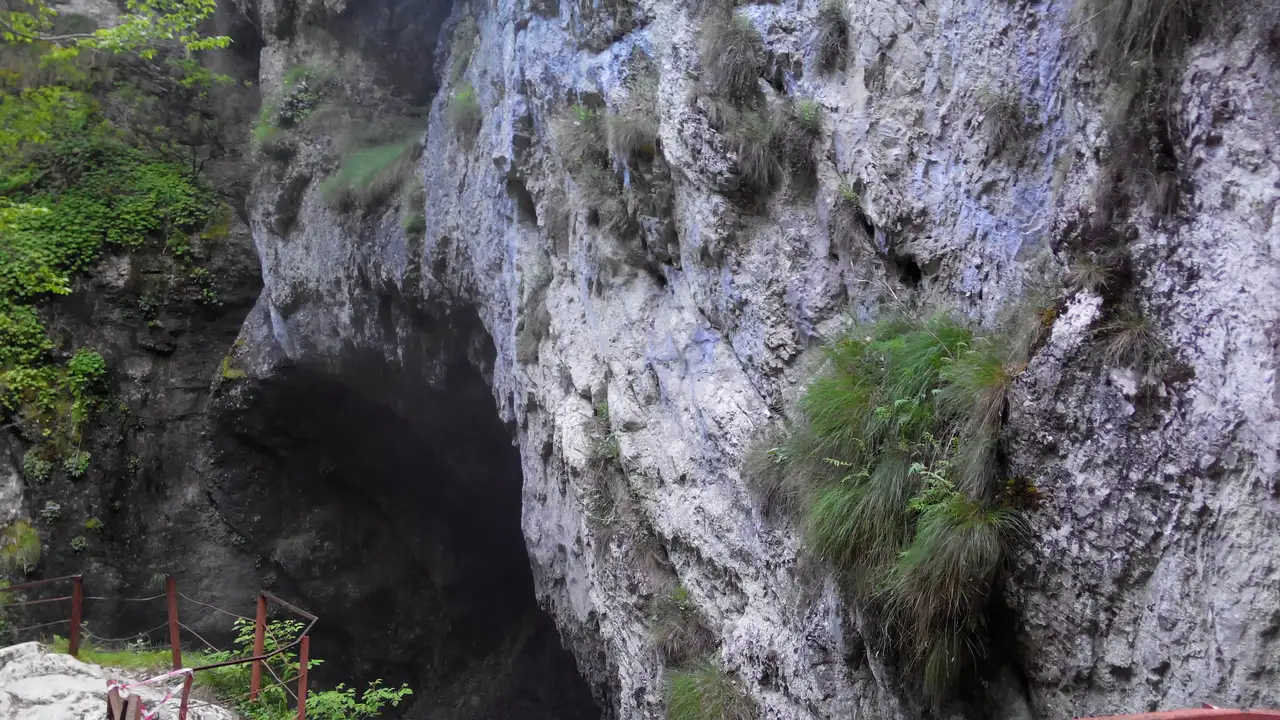The dark mouth of Devil s Throat cave opening in a pale limestone cliff face in the Trigrad gorge