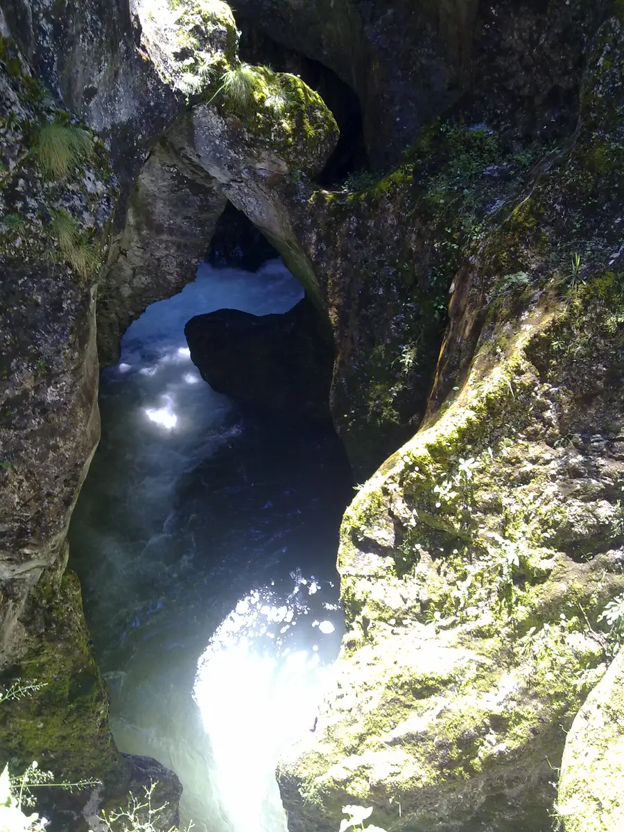 The Trigrad river dropping into a narrow rock cleft at the entrance of Devil s Throat cave
