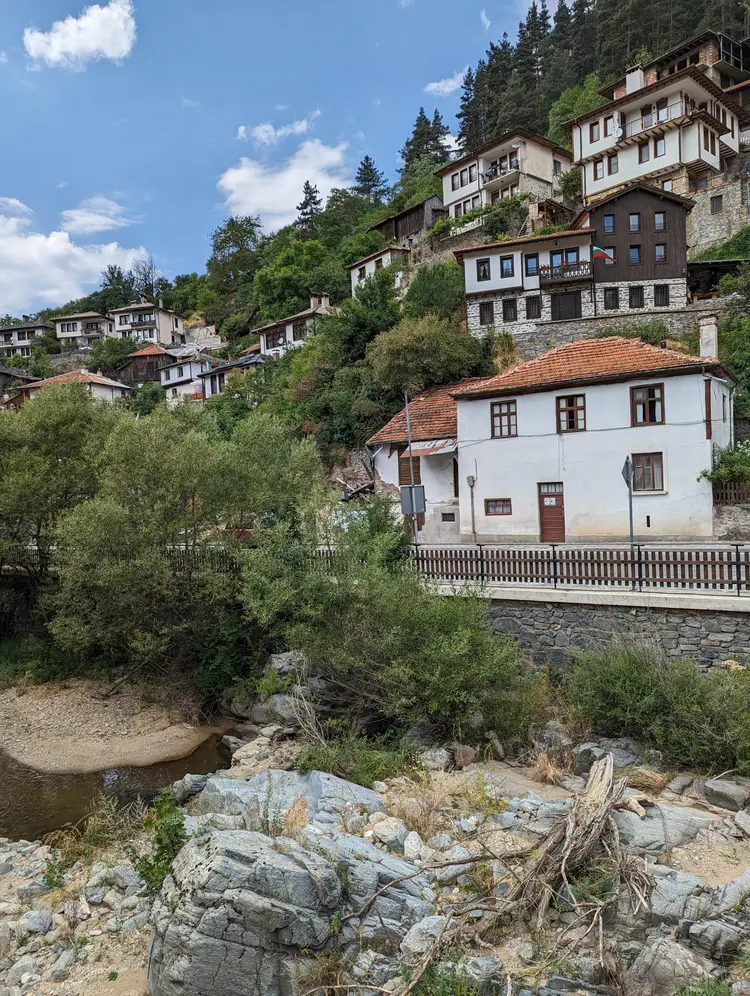 White Rhodope houses of Shiroka Laka stacked up the hillside above a stony river