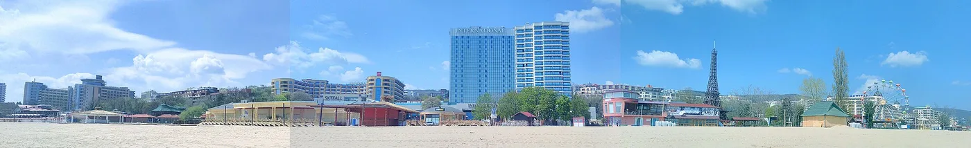 Wide view of Golden Sands from the beach, a line of resort hotels and apartment towers along the shore with an amusement area and Ferris wheel to the right