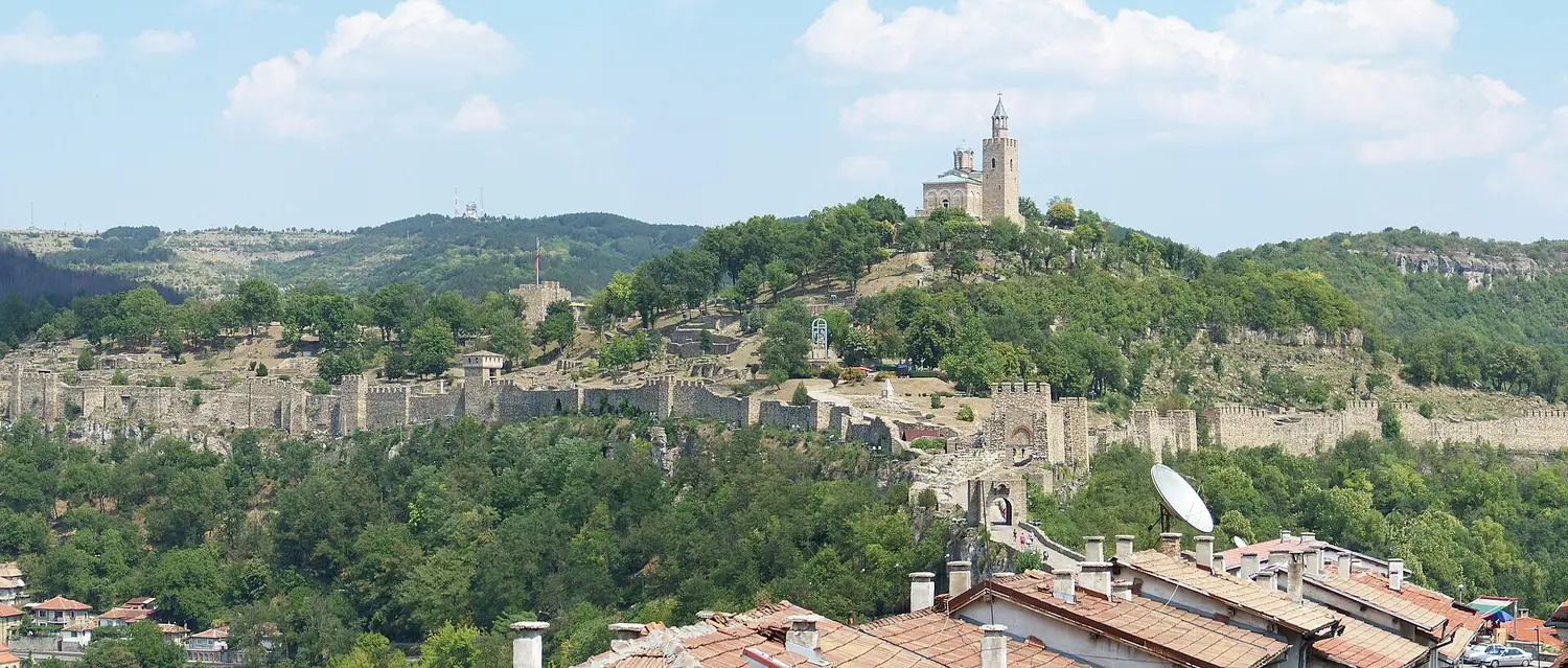 Tsarevets fortress on its wooded hill above the red rooftops of Veliko Tarnovo, the restored patriarchal church crowning the summit