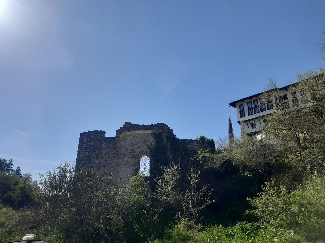 The ivy-covered stone ruin of Saint Barbara church on a knoll in Melnik, with the corner of the Kordopulov House to the right