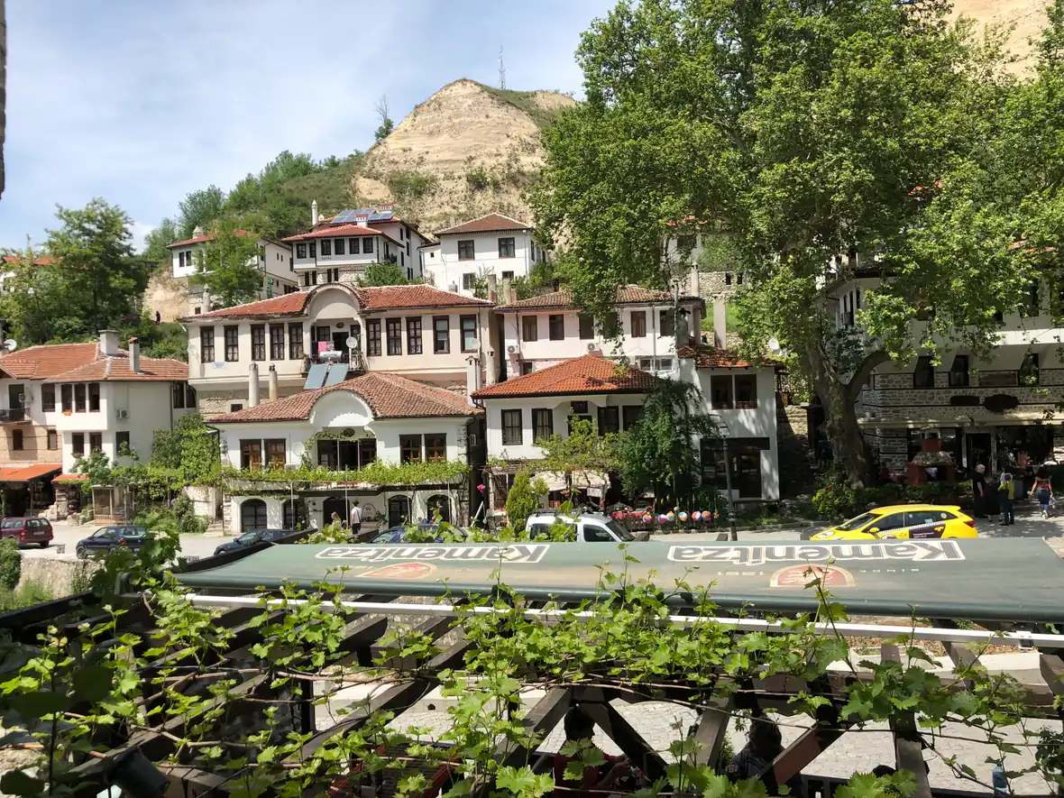 White Revival-era houses with wide upper storeys and dark window frames climbing the hillside in the centre of Melnik
