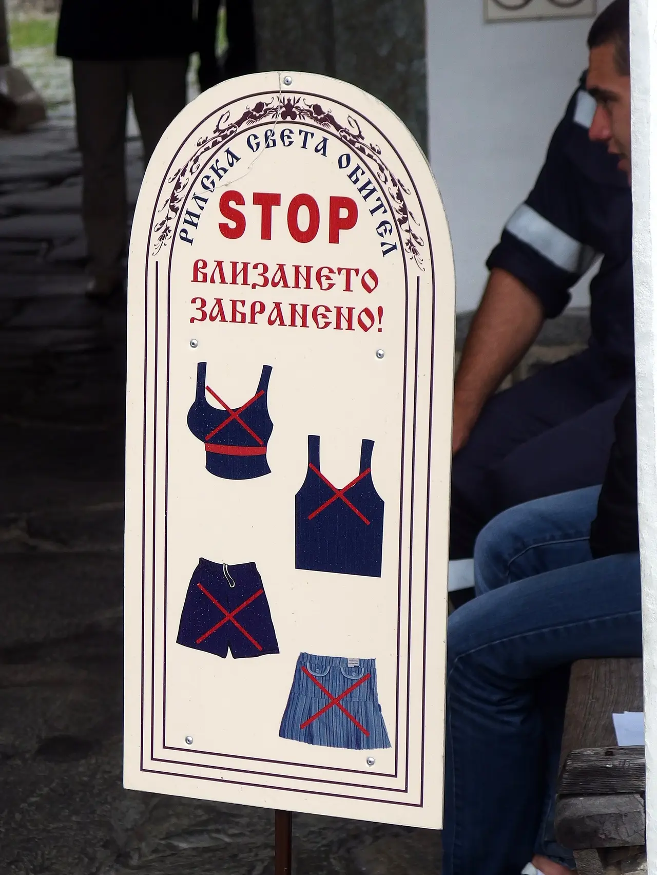 A sign at the entrance to Rila Monastery showing crossed-out crop tops, vests, shorts and short skirts