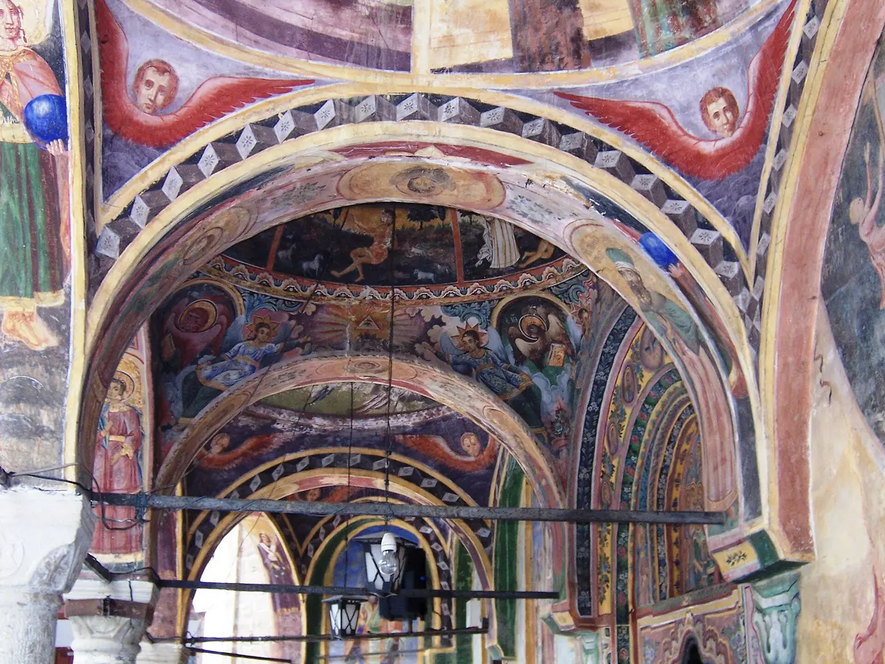 The painted vaults and arches of the open porch at Troyan Monastery, covered in 19th-century frescoes