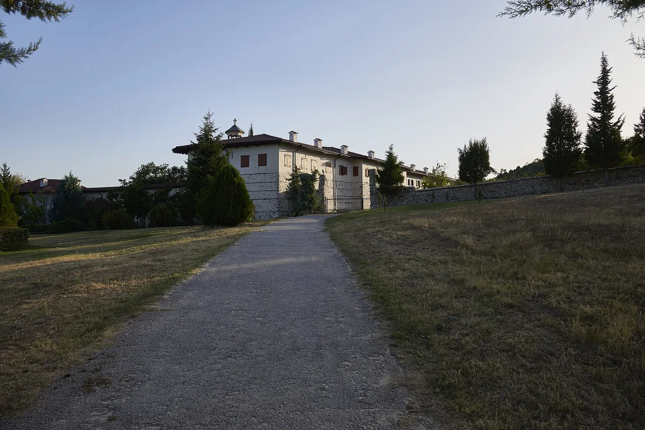 Wooden galleries and a vine-shaded stone courtyard at Rozhen Monastery in the Pirin foothills