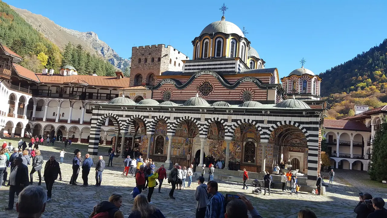 Striped arcades and the church of Rila Monastery around its cobbled courtyard