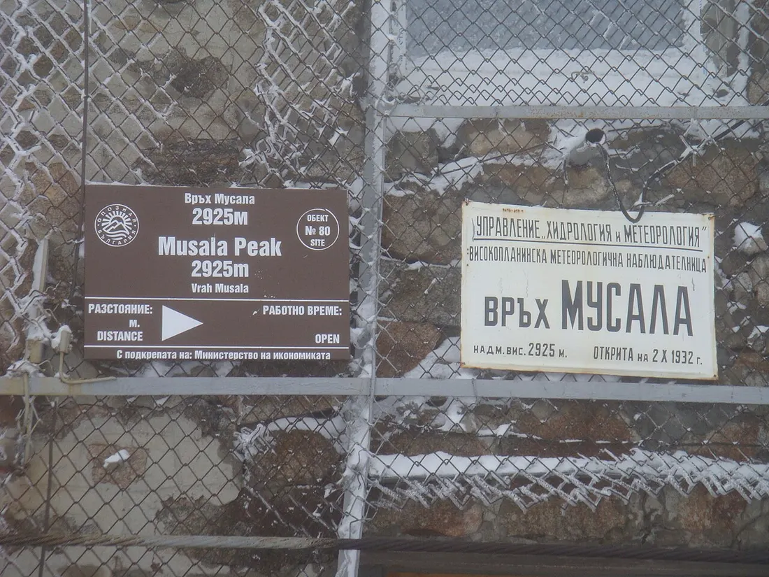 Two metal plaques on a stone wall at Musala summit, one marking the peak at 2925 m and the other the meteorological station opened in 1932