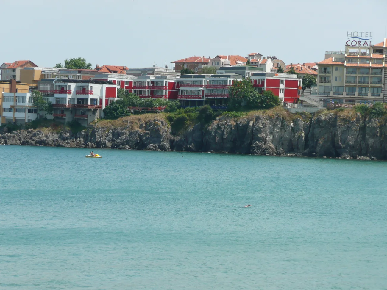 The new town of Sozopol on a low cliff above turquoise water, white-and-red apartment blocks and hotels with a pedalo on the sea below