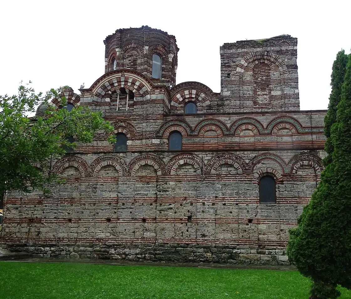 Detailed view of the outer wall of Christ Pantocrator in Nessebar showing bands of brick and stone, blind arches and green ceramic discs