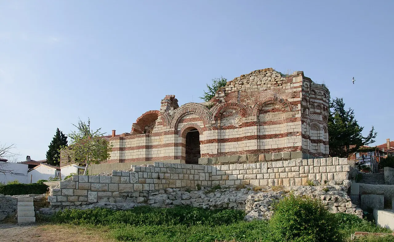 The roofless 14th-century Church of St John Aliturgetos in Nessebar, its banded brick and stone walls standing on a terrace above the sea