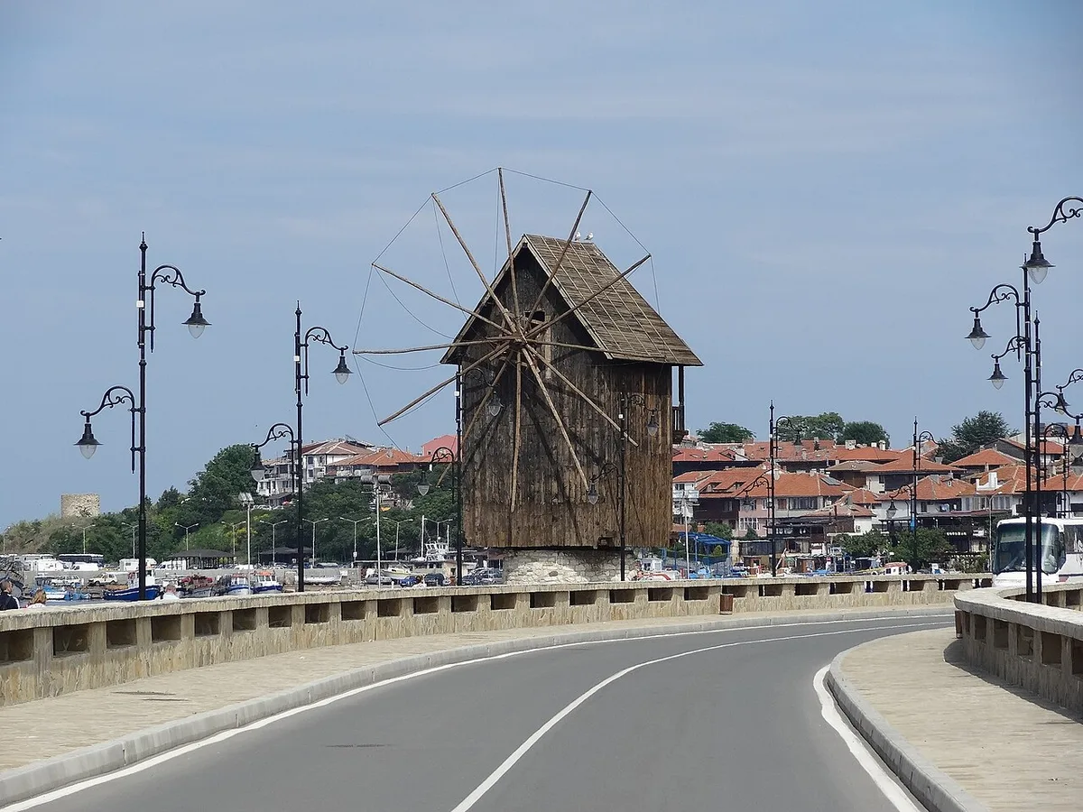 The old wooden windmill on the causeway at the entrance to Nessebar old town, with the red-tiled rooftops of the peninsula behind