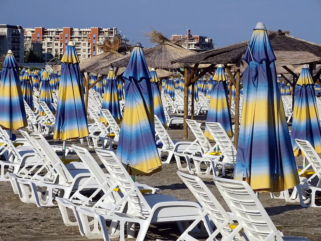 A wide sandy beach at Sunny Beach on Bulgaria's Black Sea coast crowded with sunbeds and umbrellas, the sea on one side and hotels behind