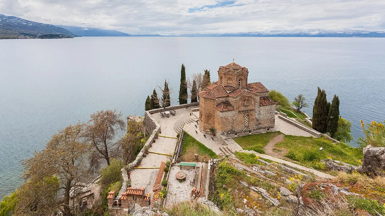 The stone Church of St John at Kaneo on a cliff above the still blue water of Lake Ohrid in North Macedonia at dusk