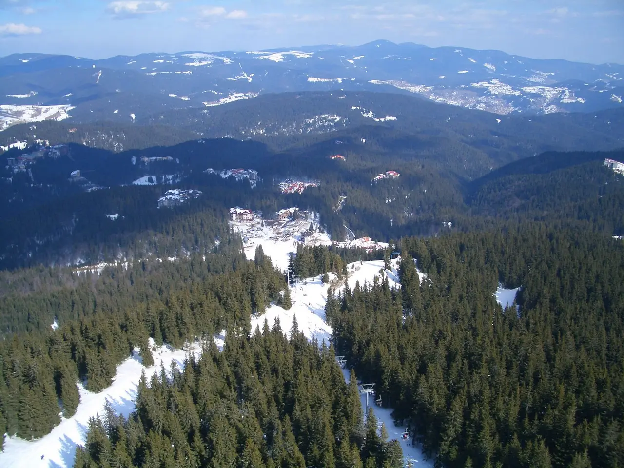 Aerial view of the Pamporovo resort set in the rolling, forested Rhodope Mountains under patchy snow