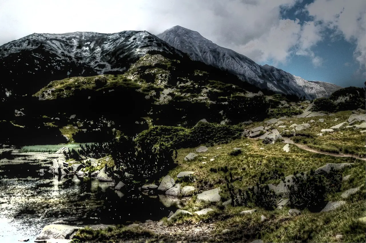 Ribnoto glacial lake reflecting Pirin ridges under broken cloud