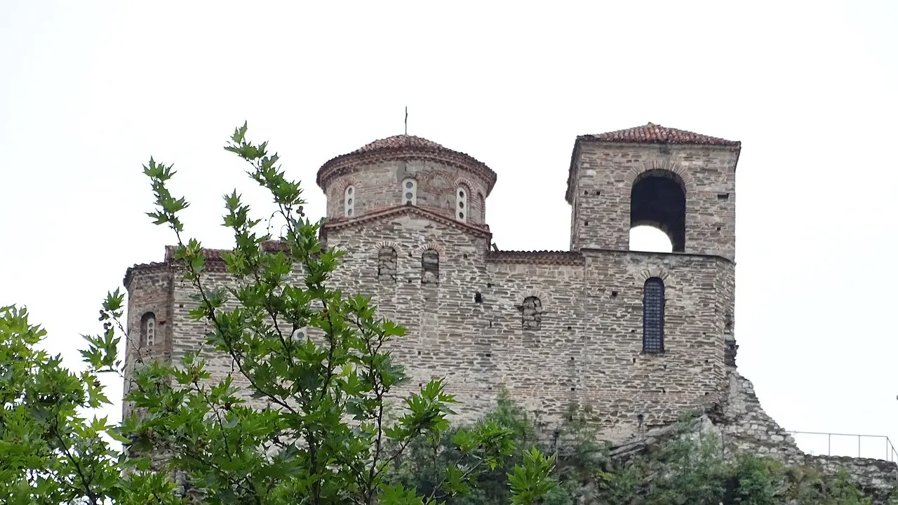 The stone arcades and church roof of Bachkovo Monastery against the wooded Rhodope slopes