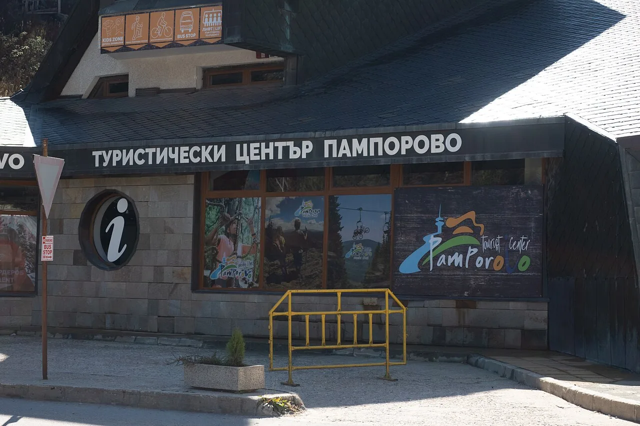 The Pamporovo tourist centre building with an information sign and a bus stop pictogram