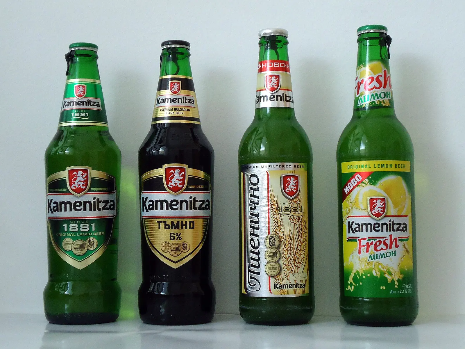 Four bottles of Kamenitza, a Bulgarian beer brand, lined up against a plain background
