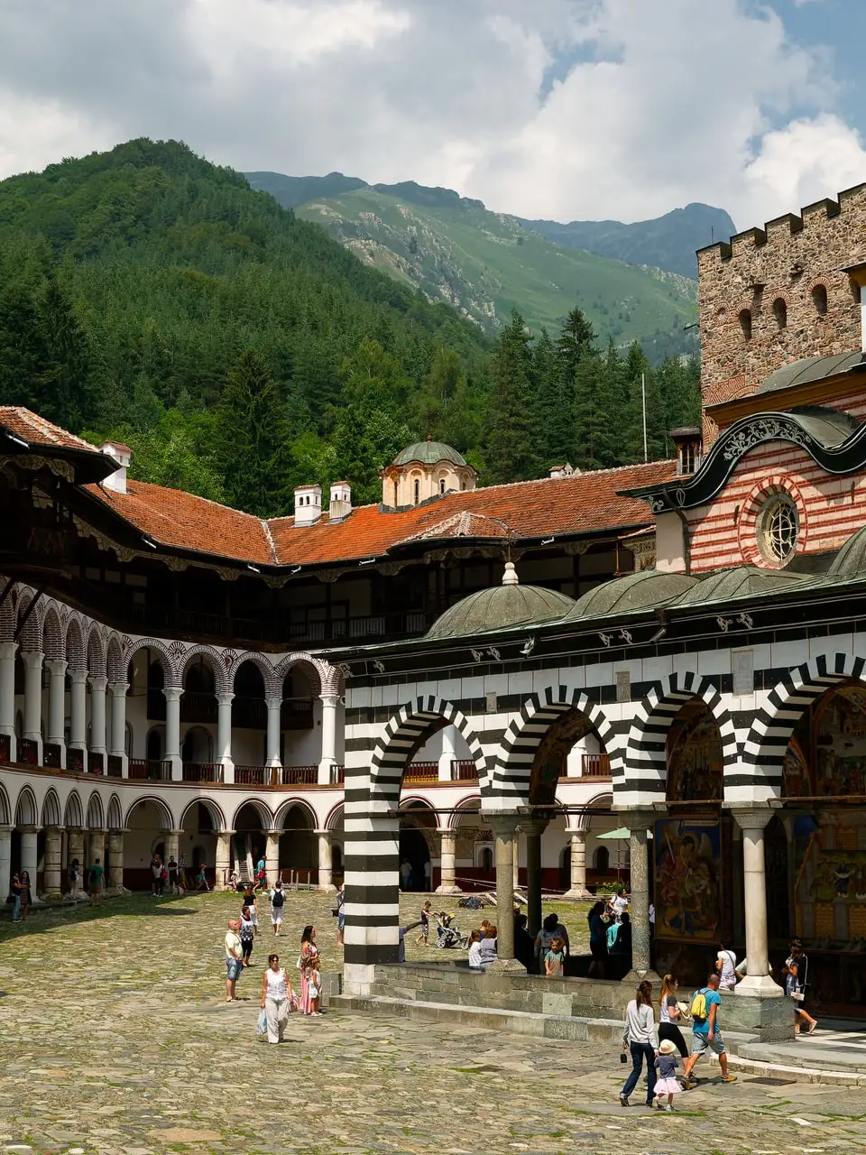 The black and white striped arches and arcaded galleries of Rila Monastery with the Rila mountains behind