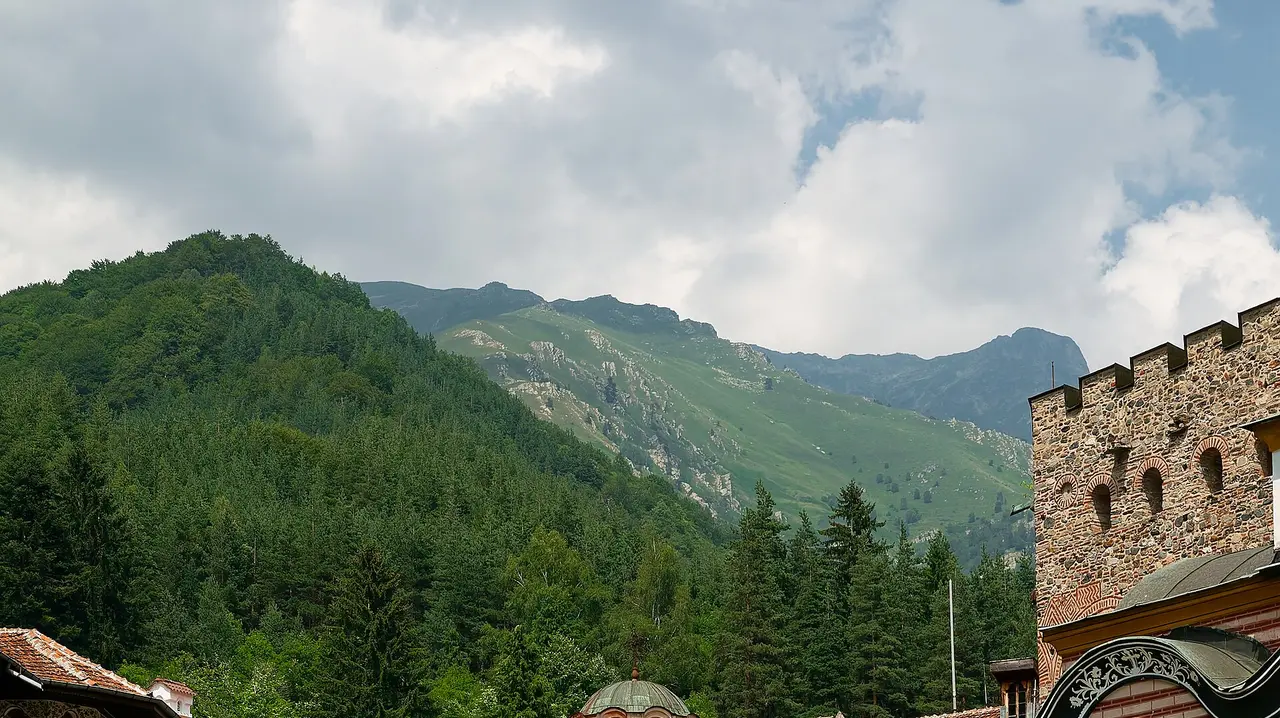 The black and white striped arches and arcaded galleries of Rila Monastery with the Rila mountains behind