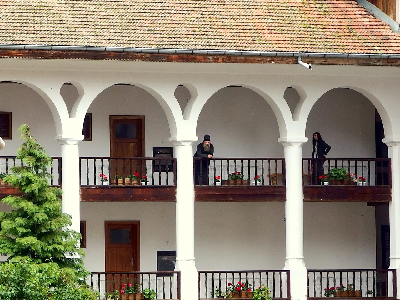 A monk and a visitor on the arcaded upper gallery of the residential wing at Rila Monastery