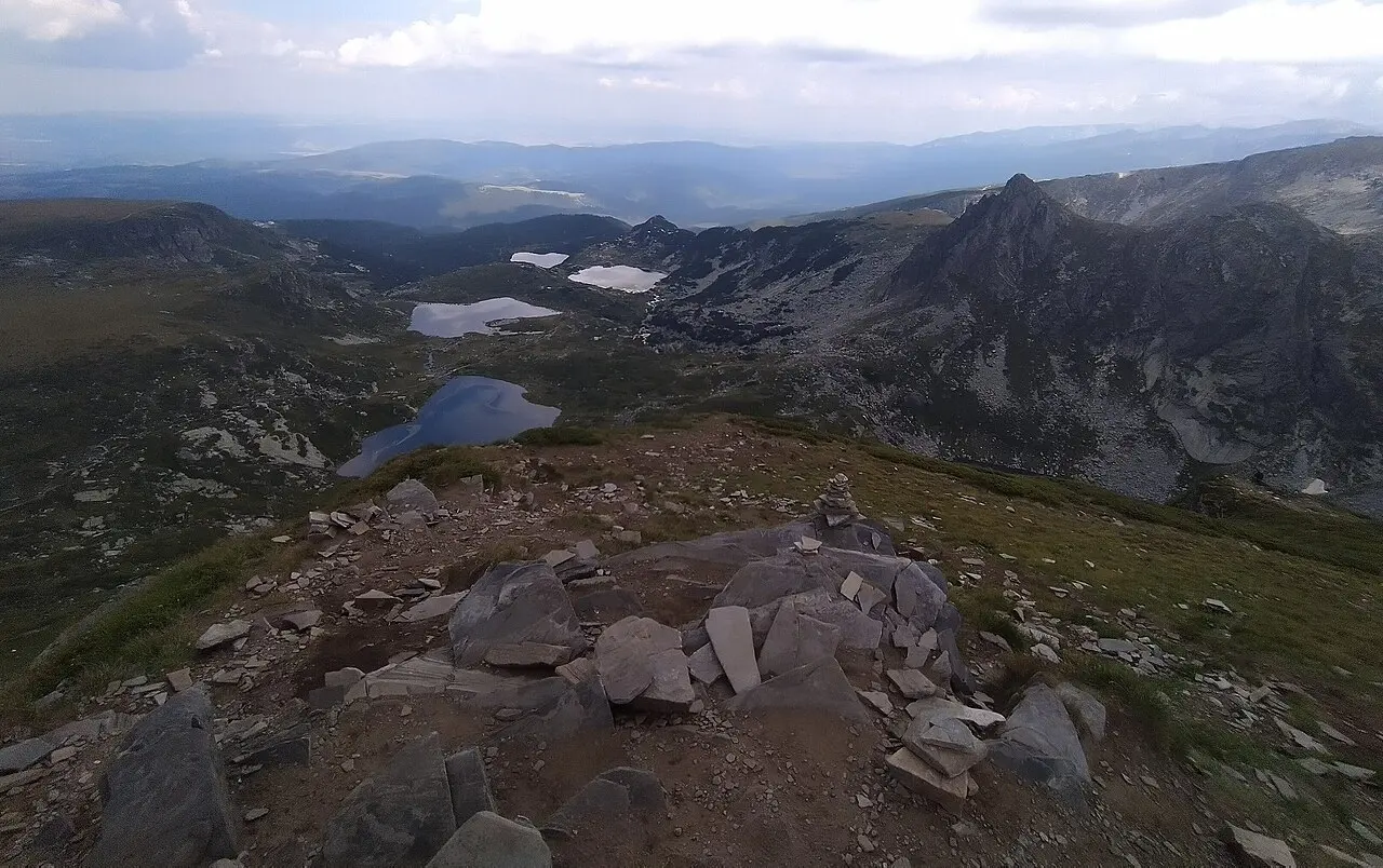 Several of the Seven Rila Lakes seen from a summit cairn, blue water in a rocky alpine basin