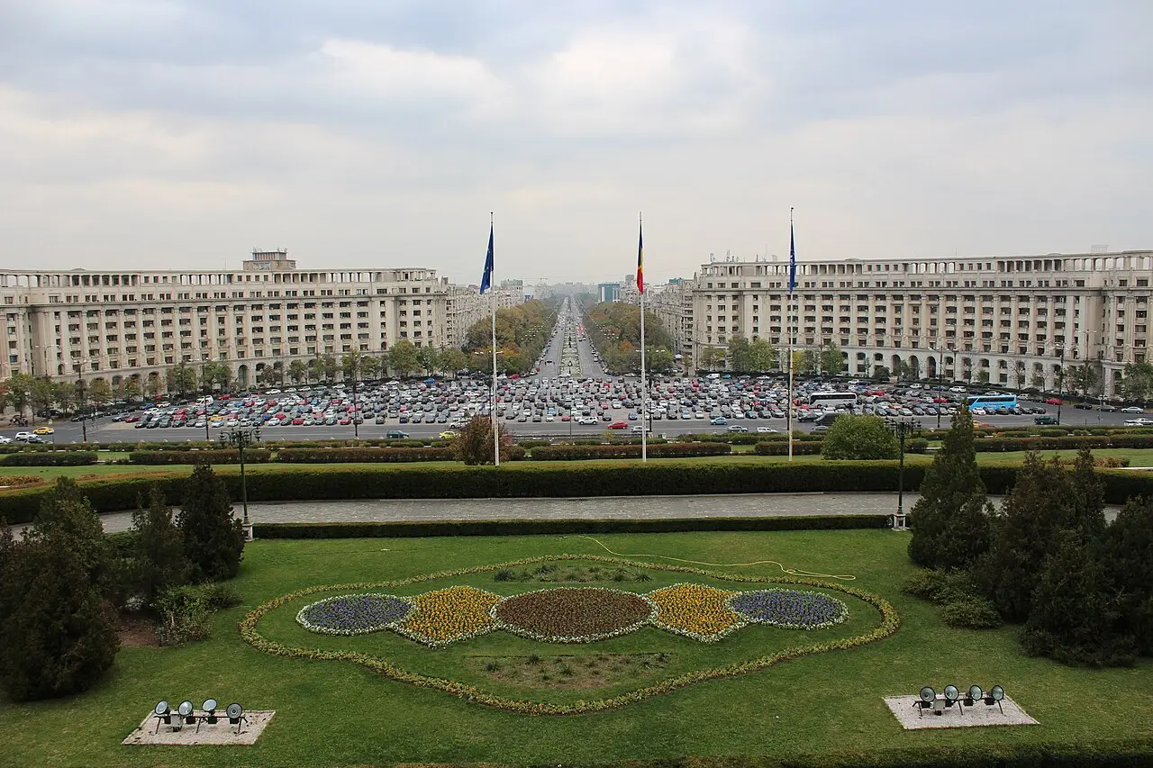The vast neoclassical facade of the Palace of the Parliament in Bucharest under a blue sky